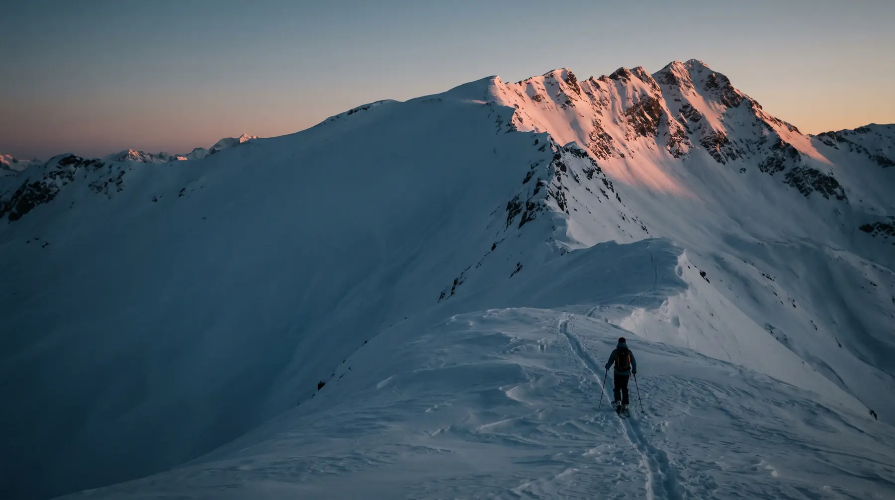 Tourengeher im ersten Licht auf einem Schneegrat